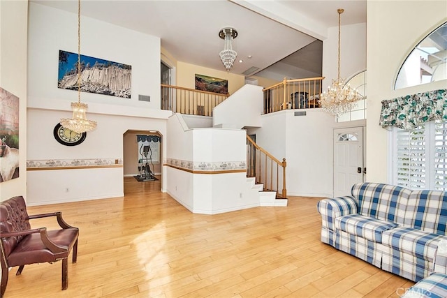 living area featuring a chandelier, stairway, beamed ceiling, hardwood / wood-style floors, and arched walkways