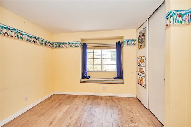 unfurnished room featuring baseboards and wood-type flooring