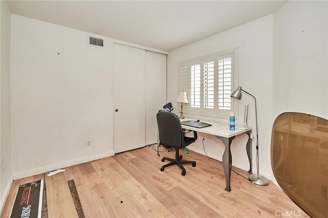 office area with visible vents, light wood-style flooring, and baseboards