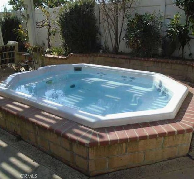 view of swimming pool with an outdoor hot tub and fence