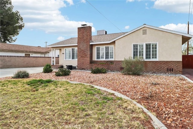 rear view of house with brick siding, a chimney, stucco siding, and fence