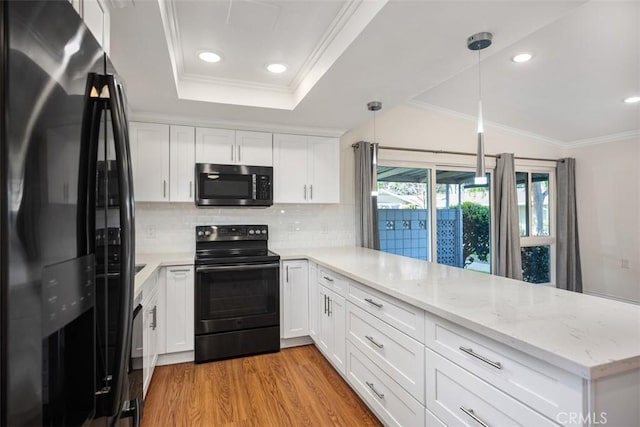 647 Avenida Sevilla Unit A, Laguna Woods, CA 92637 - kitchen with light wood-style floors, a peninsula, white cabinetry, black appliances, and backsplash