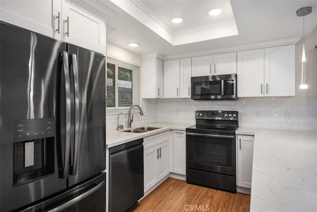 647 Avenida Sevilla Unit A, Laguna Woods, CA 92637 - kitchen with white cabinetry, black appliances, light wood-style floors, a tray ceiling, and a sink