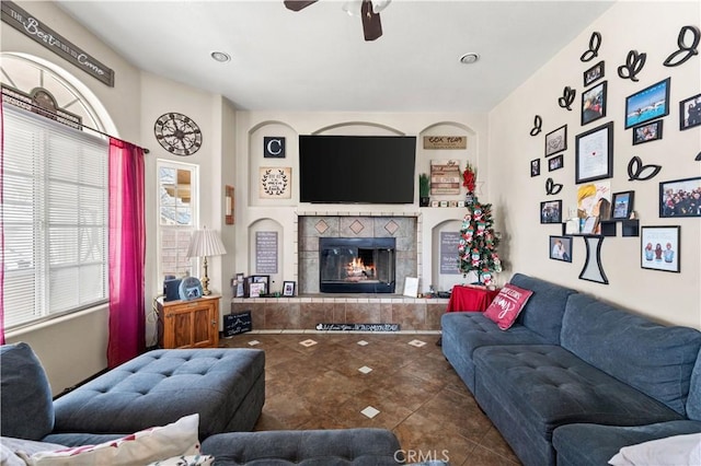 tiled living area with a tiled fireplace and a ceiling fan