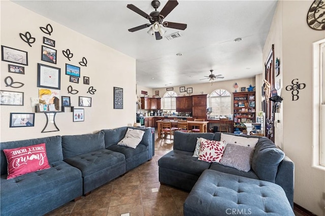 living room with dark tile patterned floors, visible vents, and ceiling fan
