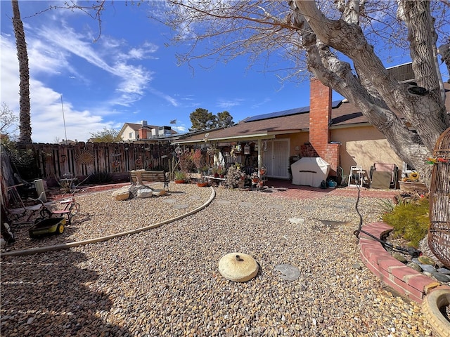 433 Oakmont Dr, Barstow, CA 92311 - back of property featuring fence, roof mounted solar panels, stucco siding, a chimney, and a patio
