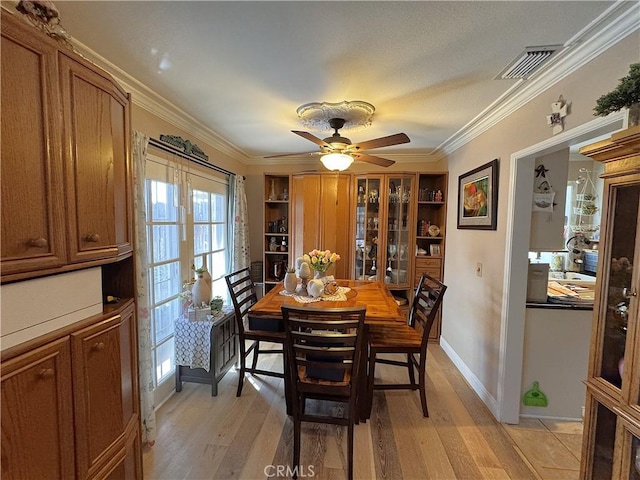 433 Oakmont Dr, Barstow, CA 92311 - dining room featuring visible vents, light wood-style flooring, crown molding, baseboards, and ceiling fan
