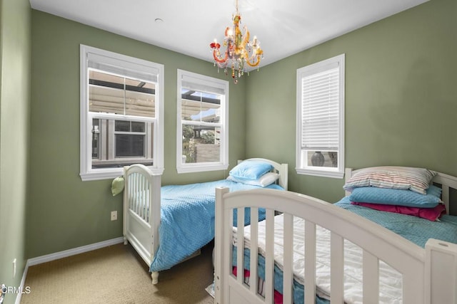 bedroom featuring carpet flooring, multiple windows, baseboards, and an inviting chandelier