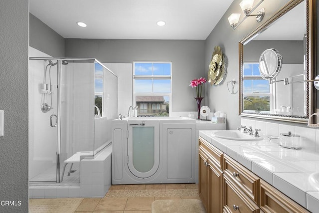 full bath with tile patterned flooring, double vanity, a stall shower, and a sink