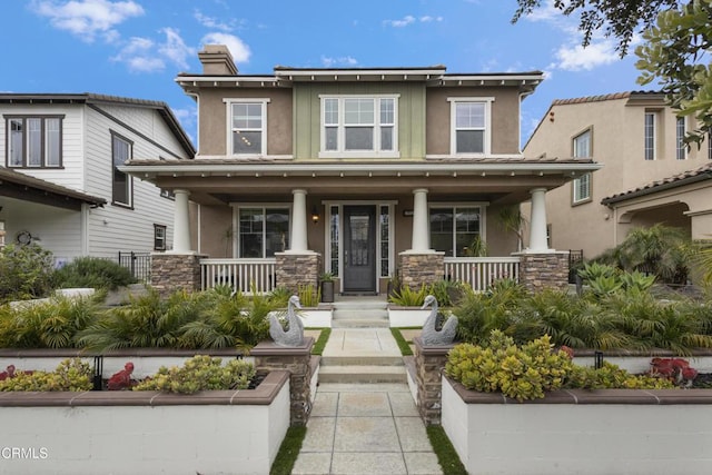 view of front of house featuring stucco siding, stone siding, and a porch