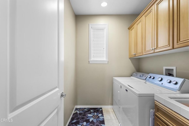 clothes washing area featuring cabinet space, light tile patterned floors, washer and dryer, and baseboards