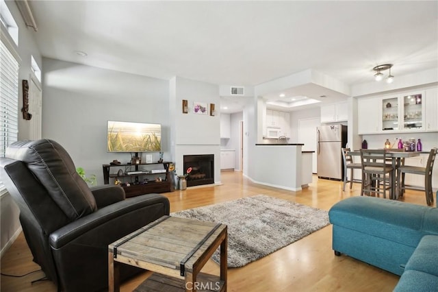 living room featuring light wood-style floors, a fireplace, baseboards, visible vents, and recessed lighting