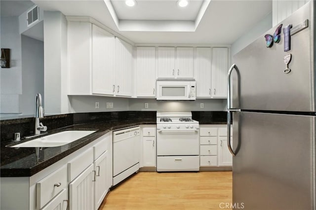 kitchen featuring light wood-type flooring, white appliances, a sink, and white cabinetry
