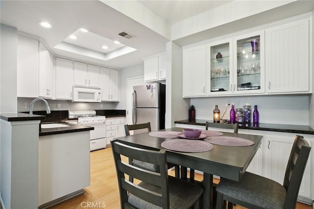 kitchen featuring visible vents, white appliances, white cabinetry, and a tray ceiling