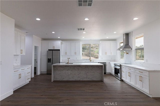 kitchen with visible vents, appliances with stainless steel finishes, wall chimney exhaust hood, and white cabinets