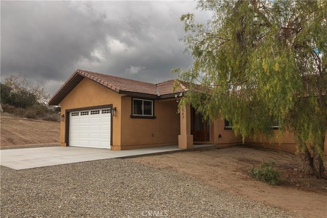 single story home with concrete driveway, a tiled roof, a garage, and stucco siding