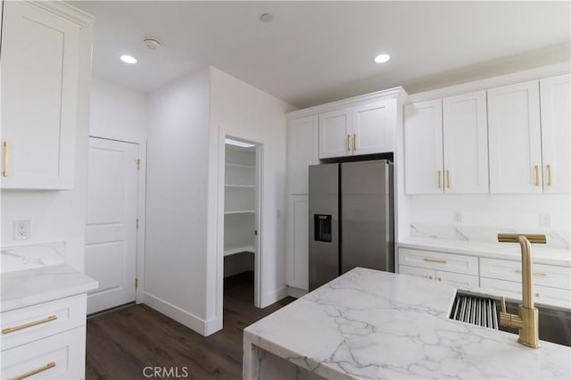 kitchen with light stone counters, recessed lighting, stainless steel fridge with ice dispenser, and white cabinetry