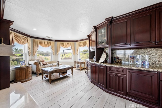 interior space featuring ornamental molding, a textured ceiling, light wood-style flooring, and a healthy amount of sunlight