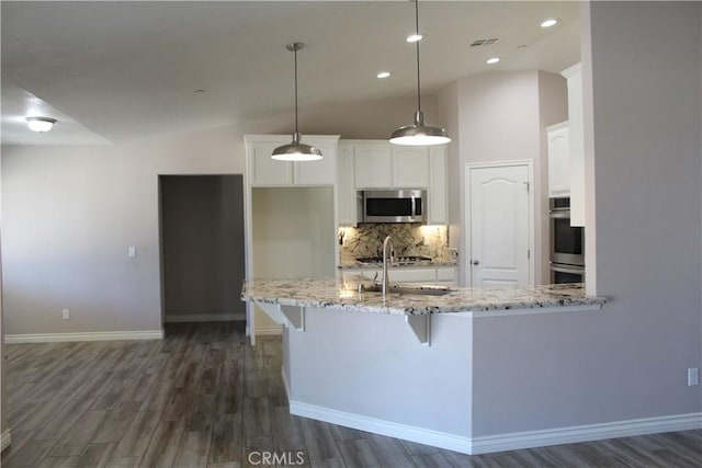 kitchen with light stone countertops, appliances with stainless steel finishes, dark wood-style flooring, and white cabinets