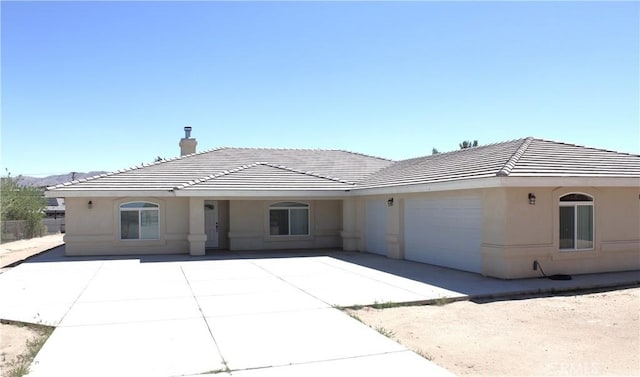 single story home with a garage, stucco siding, and a tiled roof