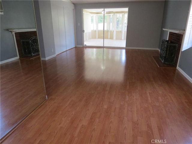 unfurnished living room featuring baseboards, wood finished floors, and a fireplace