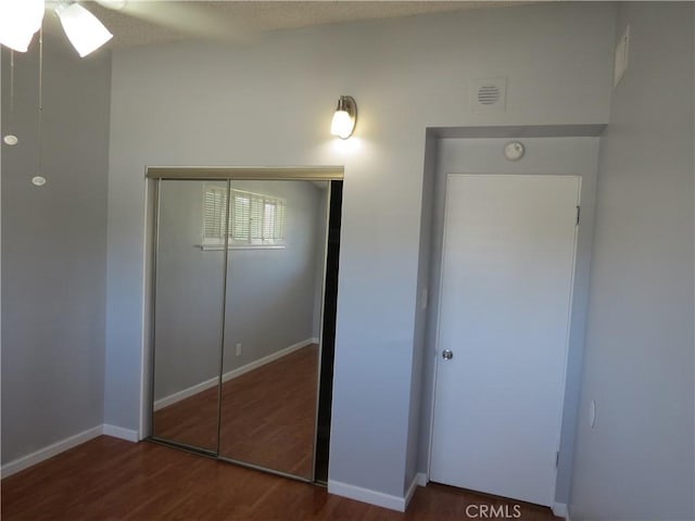 unfurnished bedroom featuring a closet, baseboards, and wood finished floors