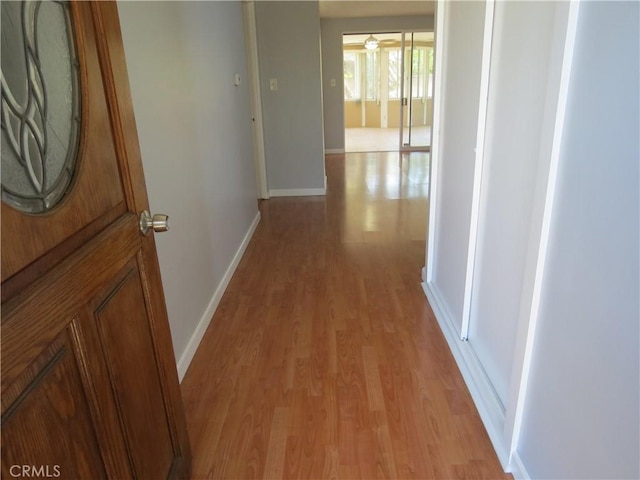 hall featuring light wood-type flooring and baseboards