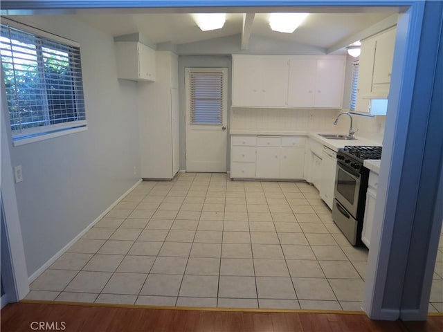 kitchen featuring backsplash, gas range, light countertops, light tile patterned floors, and a sink