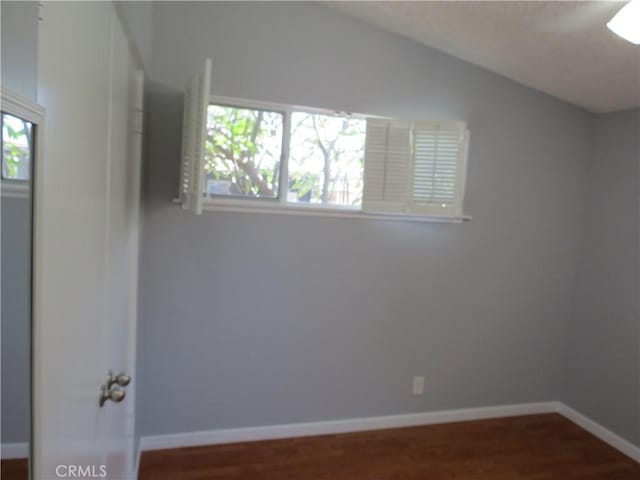 unfurnished room featuring baseboards, lofted ceiling, and wood finished floors