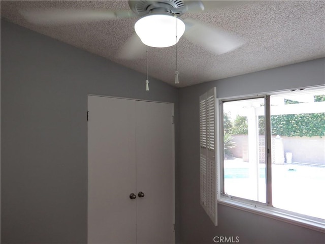 unfurnished bedroom featuring a closet, lofted ceiling, a textured ceiling, and ceiling fan