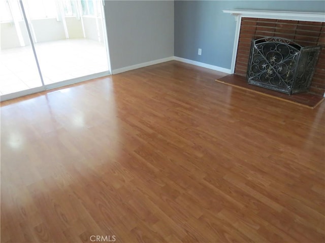 unfurnished living room featuring a fireplace, wood finished floors, and baseboards
