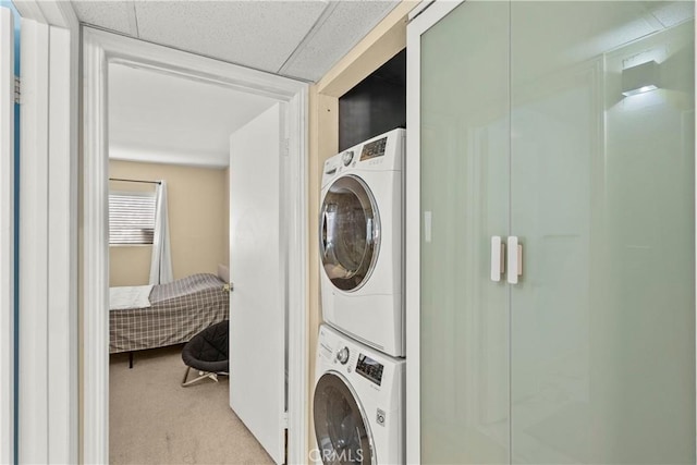 washroom featuring carpet flooring, stacked washer / dryer, and laundry area