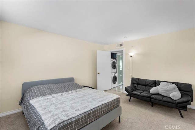 bedroom featuring stacked washer and clothes dryer, baseboards, visible vents, and light colored carpet