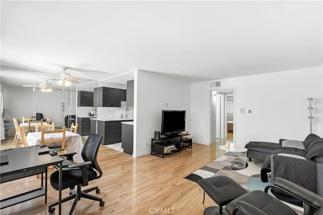 living room with a ceiling fan, light wood-style flooring, and visible vents