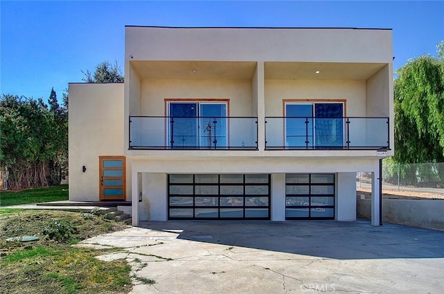 21655 Temescal Canyon Rd, Corona, CA 92883 - contemporary house featuring a balcony, a garage, driveway, and stucco siding