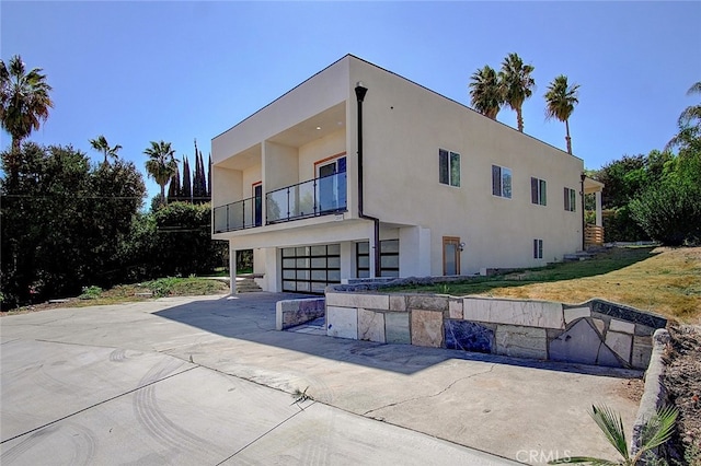 21655 Temescal Canyon Rd, Corona, CA 92883 - back of house with a balcony, an attached garage, driveway, and stucco siding