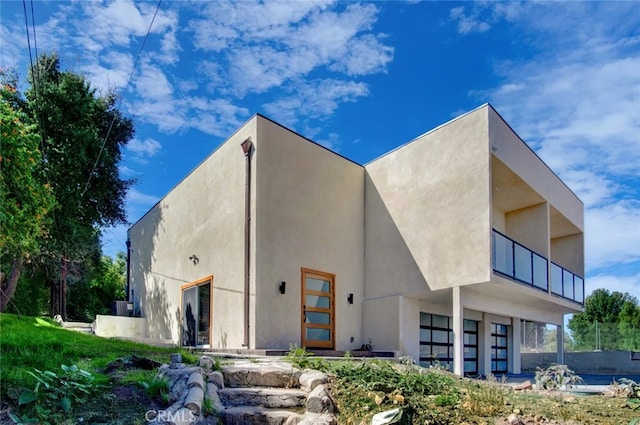21655 Temescal Canyon Rd, Corona, CA 92883 - rear view of house with stucco siding, an attached garage, and a balcony