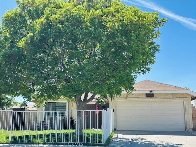 36913 Tobira Dr, Palmdale, CA 93550 - view of property hidden behind natural elements featuring a garage, stucco siding, and driveway