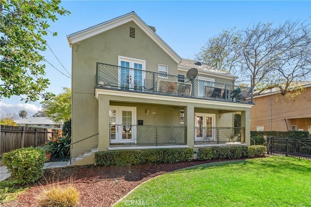 view of front of property featuring a balcony, stucco siding, and fence