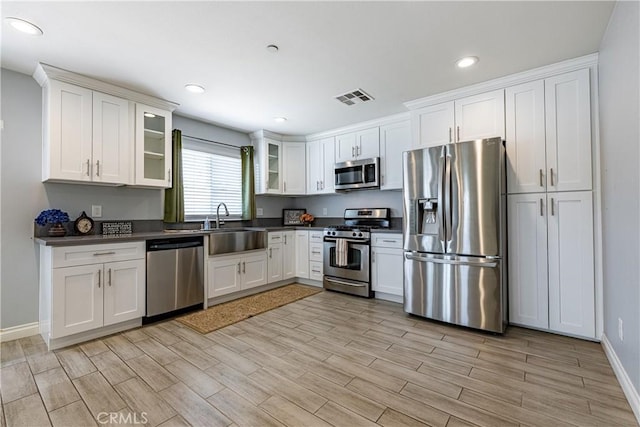 1143 Webster St, Redlands, CA 92374 - kitchen featuring dark countertops, appliances with stainless steel finishes, light wood-type flooring, and white cabinetry