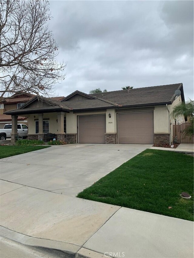 view of front facade featuring a front yard, driveway, stucco siding, a garage, and stone siding