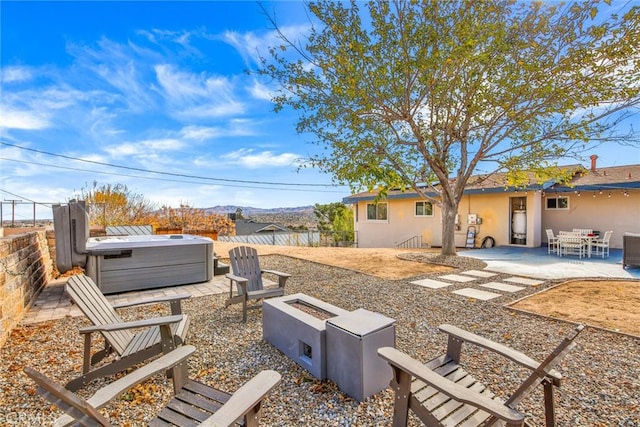 view of yard featuring a mountain view, a patio, an outdoor fire pit, a hot tub, and a fenced backyard