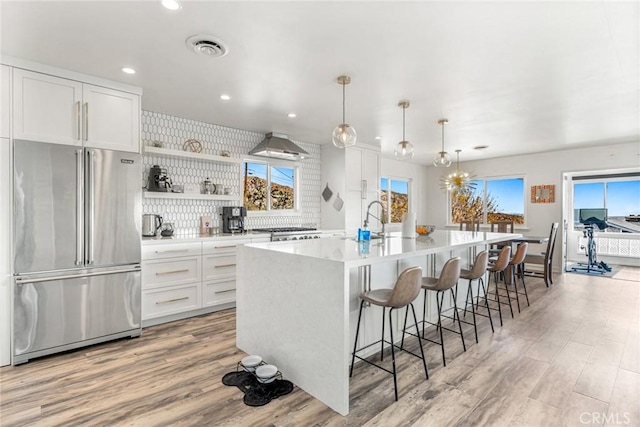 kitchen with recessed lighting, light wood-style floors, an island with sink, and high end refrigerator
