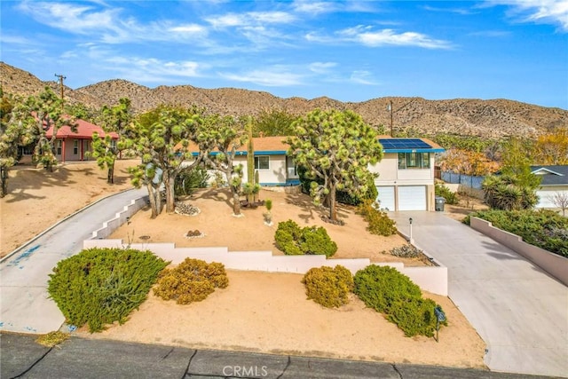 view of front facade featuring concrete driveway, stucco siding, a garage, and a mountain view