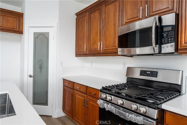 1677 Catania Dr, Riverside, CA 92507 - kitchen featuring light countertops, brown cabinets, wood finished floors, and appliances with stainless steel finishes