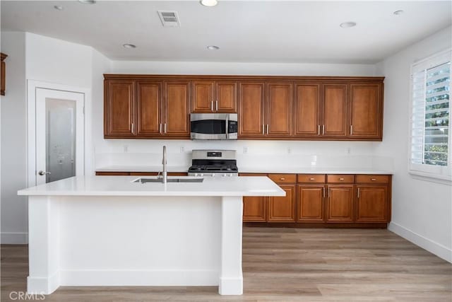 1677 Catania Dr, Riverside, CA 92507 - kitchen with light countertops, stainless steel appliances, an island with sink, visible vents, and brown cabinetry