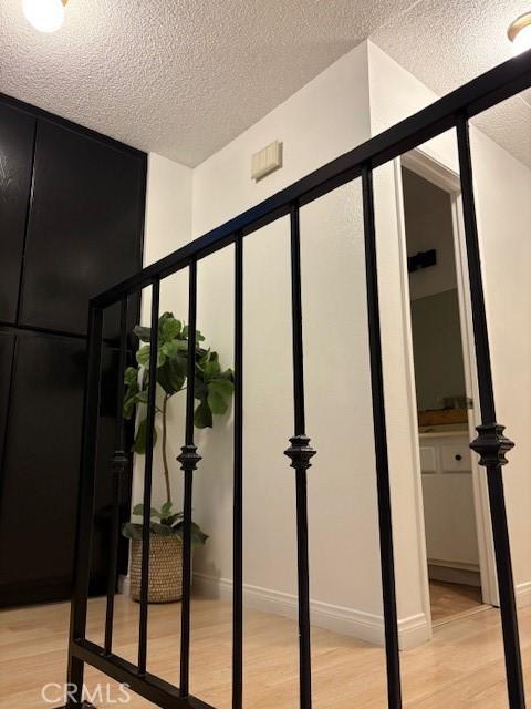 interior space with baseboards, wood finished floors, and a textured ceiling