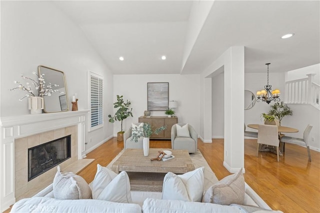 living room with vaulted ceiling, wood finished floors, a fireplace, a notable chandelier, and recessed lighting