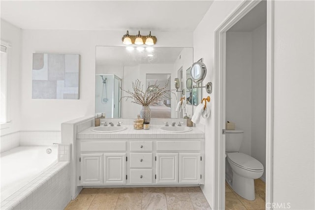 full bath featuring a bath, double vanity, toilet, and a sink