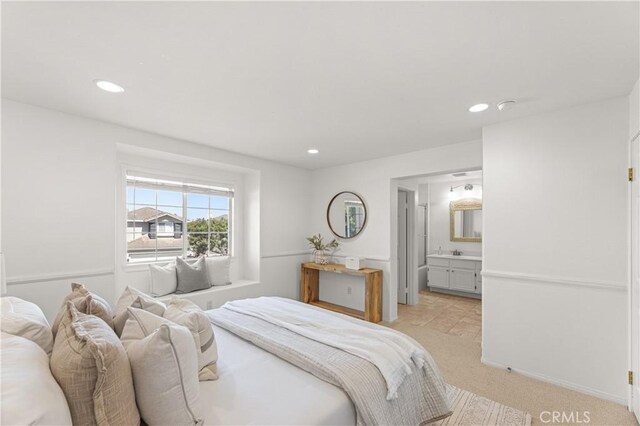 bedroom featuring light carpet, ensuite bath, and recessed lighting